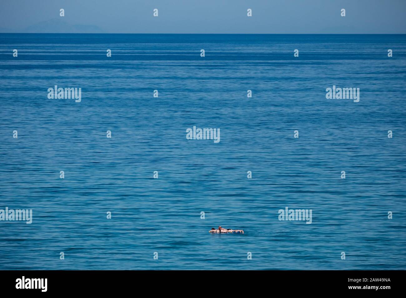 Une grande vue de la mer et de l'horizon sans terre visible avec un couple sur les inflatables flottant dans une vaste étendue d'eau. Banque D'Images