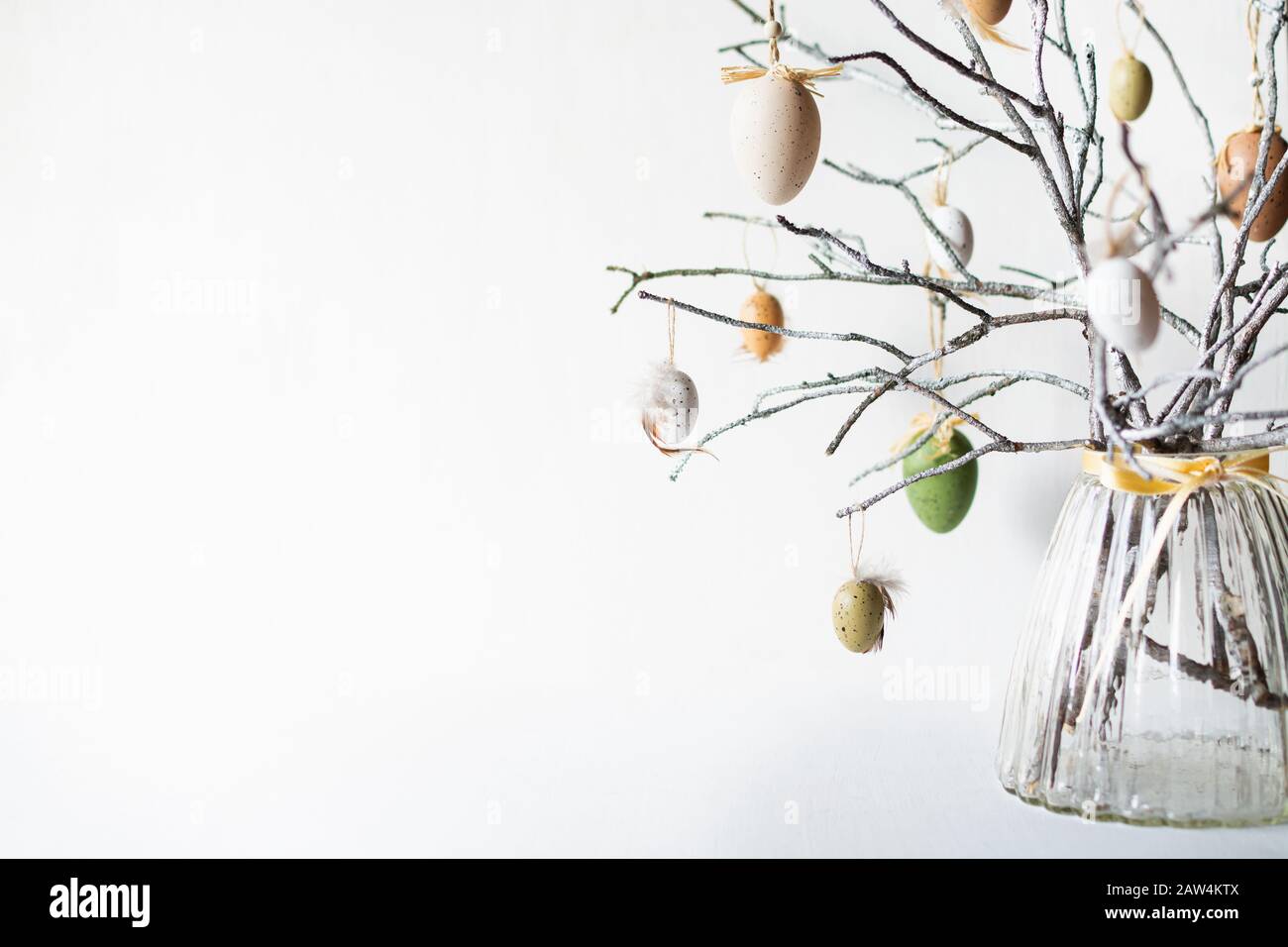 Toujours la vie avec des branches d'arbres décorées avec des œufs de Pâques et des plumes dans un vase en verre Banque D'Images