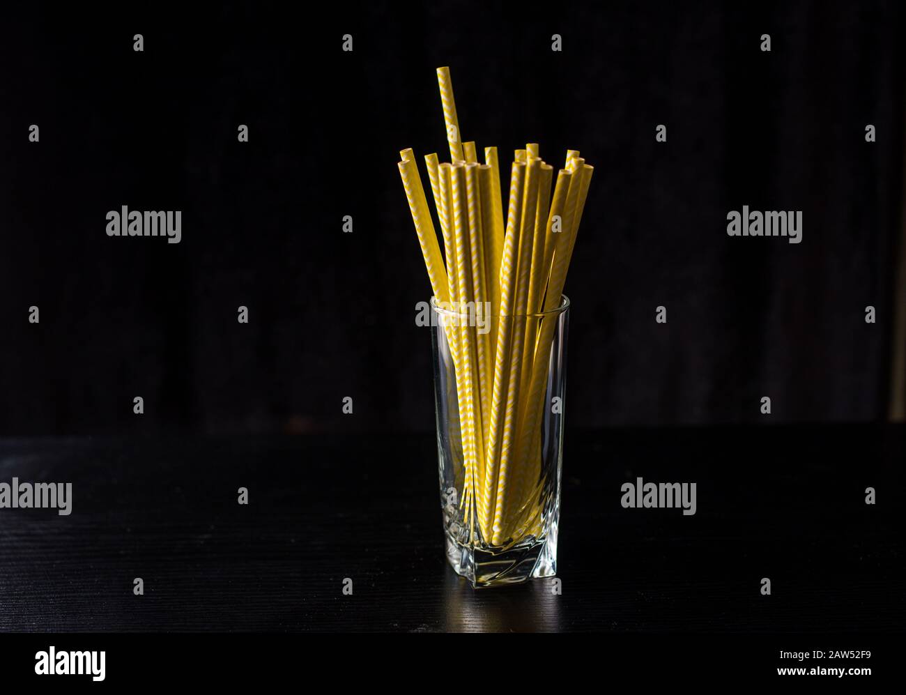 Beaucoup de tubes jaunes dans un verre sur fond noir. Boissons Banque D'Images