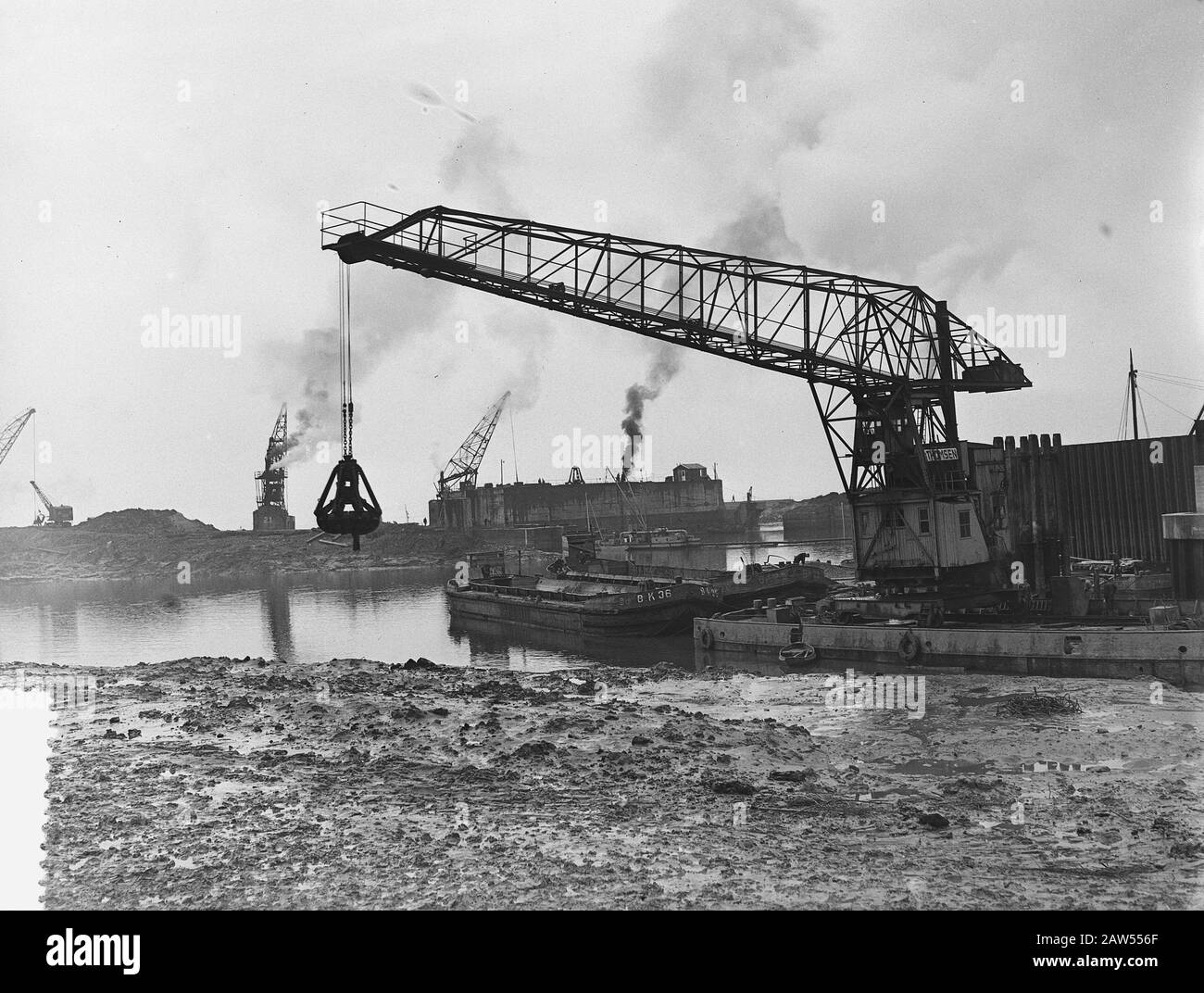 Nettoyage. Caissons dans la zone de catastrophe de Kruiningen. Veerhaven Kruiningen, répare après les inondations de 1953 et avec des caissons étanchéifier le trou d'écoulement dans le terminal de ferry en juillet 1953. Grue flottante spéciale avec une flèche de 30 mètres qui a été utilisée pour fournir la rampe argile nouvellement dijkgloing. Date : 23 mars 1954 lieu : Kruiningen mots clés : caissons, réparation, grues, inondation Banque D'Images