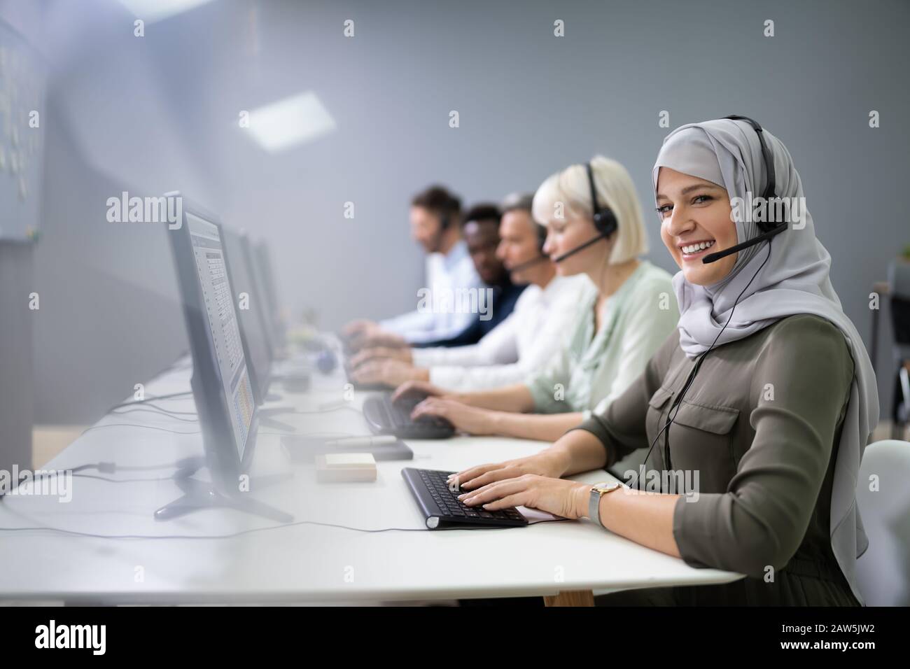 L'agent des services à la clientèle féminine positive avec casque de travail dans un centre d'appels Banque D'Images