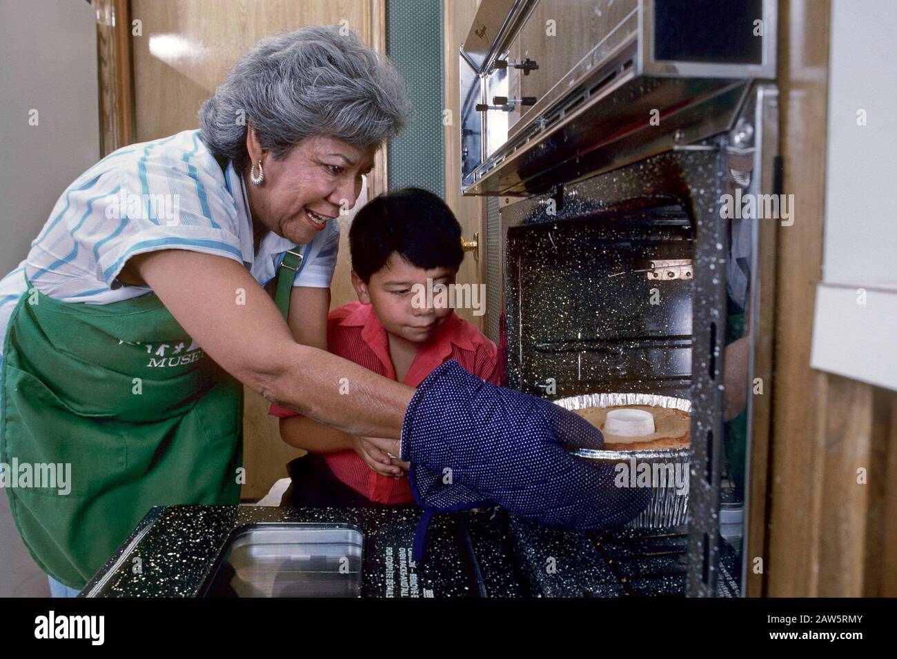 Grand-mère hispanique et petit-fils gâteau à la boulangerie ensemble dans la cuisine maison. M. ©Bob Daemmrich Banque D'Images