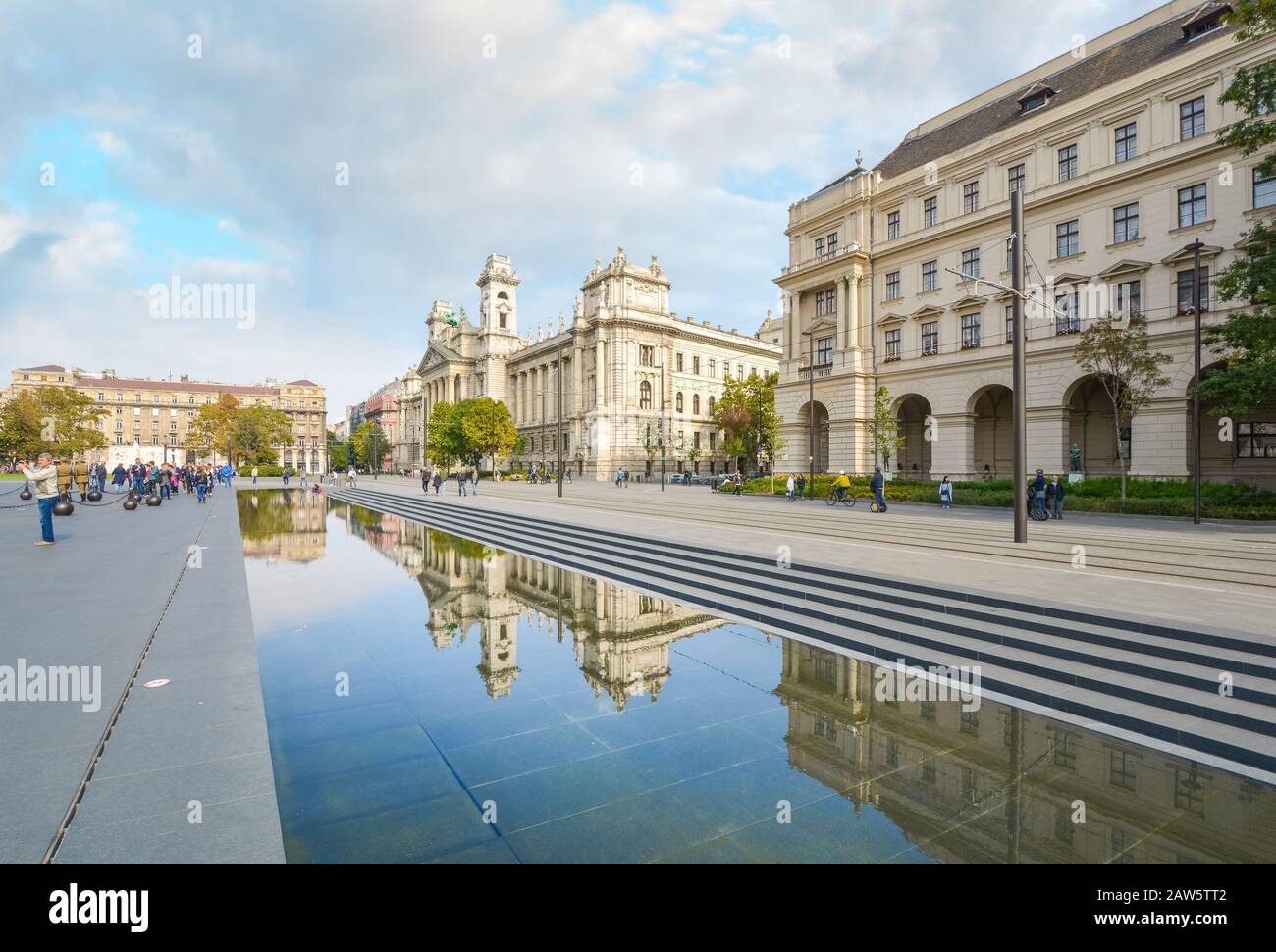 Les touristes se rendent sur la place du Parlement de Kossuth, car les bâtiments du gouvernement hongrois se reflètent dans la grande piscine réfléchissante de Budapest, en Hongrie. Banque D'Images