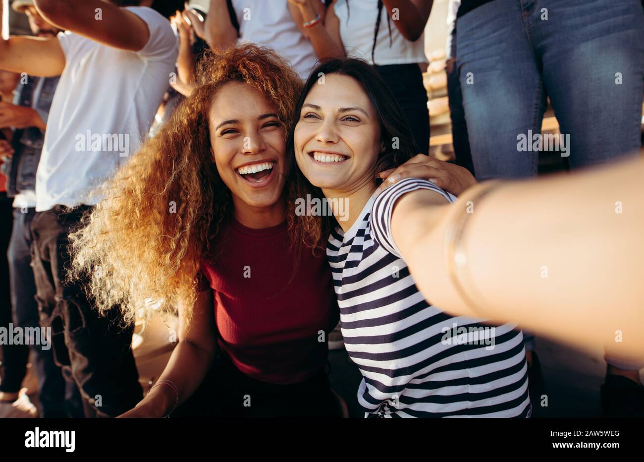 Foule dans un stade regardant un événement sportif prenant selfie. Deux femmes prenant un selfie dans le stade. Banque D'Images