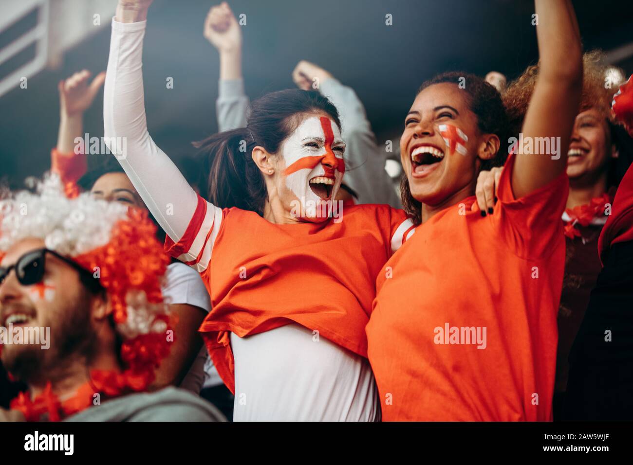 Fans de football féminin dans le stade célébrant la victoire. Les spectateurs anglais qui joueront après une victoire de championnat de football dans des stands Banque D'Images