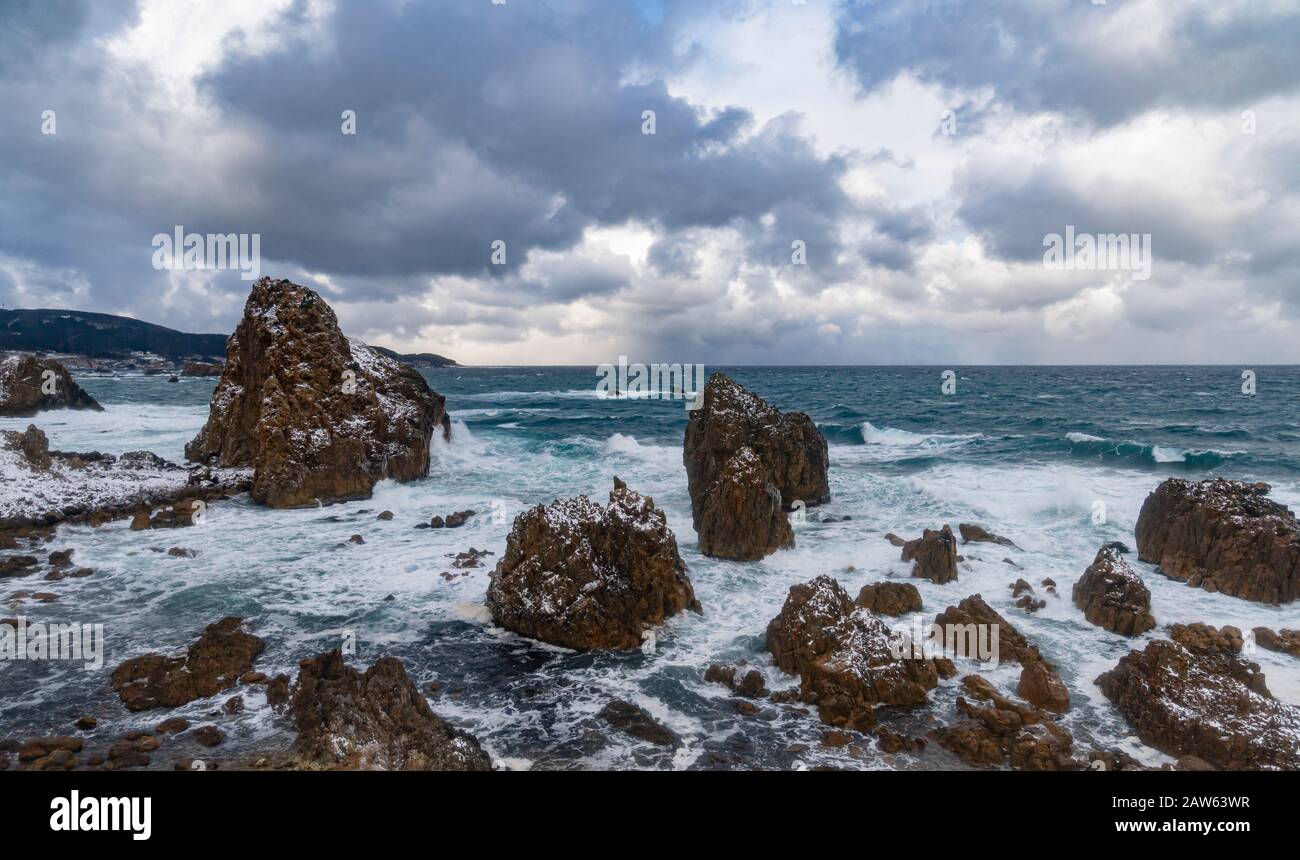 Les rochers et les rochers sur la côte de la mer du Japon dans la préfecture d'Aomori avec une jetée et un sanctuaire de Shinto, vu d'un train JR East sur la ligne Gono. Banque D'Images