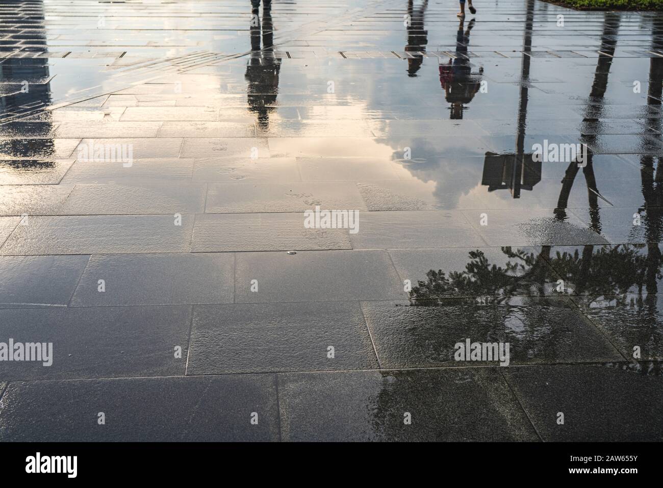 Nuages, gens et arbres reflétés dans l'eau sur la route. Banque D'Images