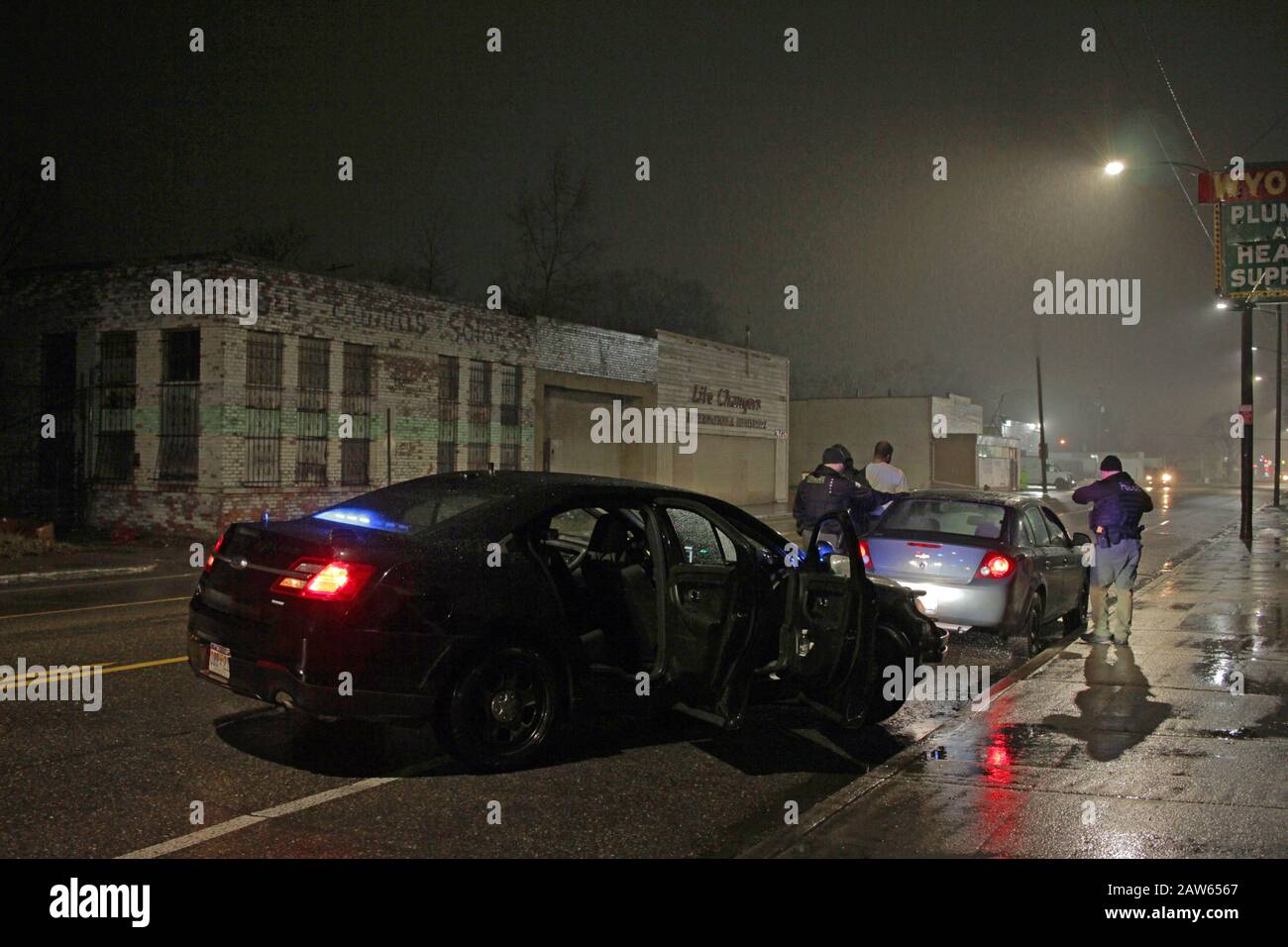 Les officiers de police spéciale de Detroit arrêtent un véhicule et parlent au conducteur lors d'une nuit de pluie à Detroit, Michigan, États-Unis Banque D'Images