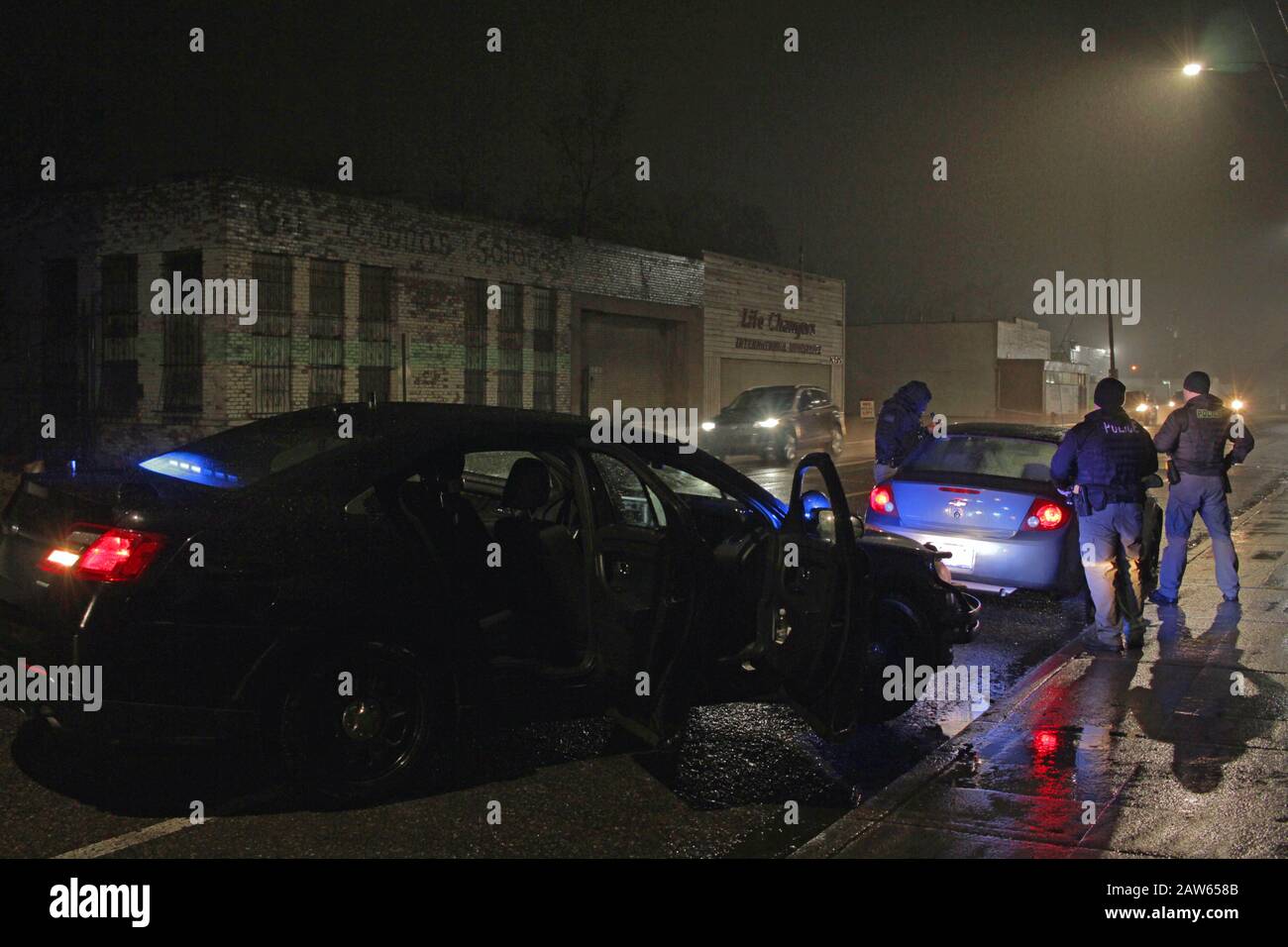 Les officiers de police spéciale de Detroit arrêtent un véhicule et parlent au conducteur lors d'une nuit de pluie à Detroit, Michigan, États-Unis Banque D'Images