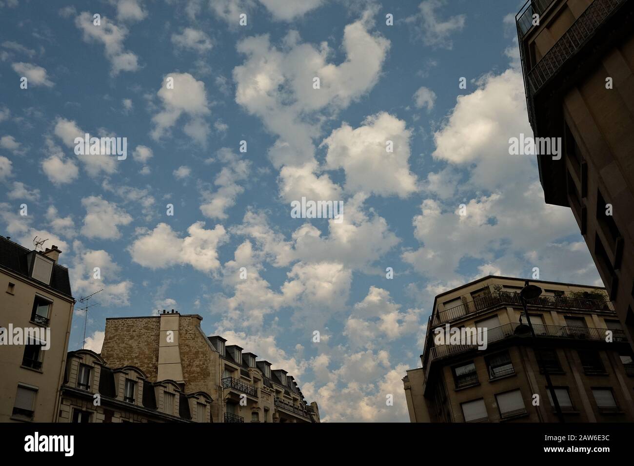 En fin d'après-midi, en été à Paris, en France, des nuages blancs moelleux flottant au-dessus des bâtiments mansardés de Paris Appartement sur un ciel bleu ensoleillé Banque D'Images