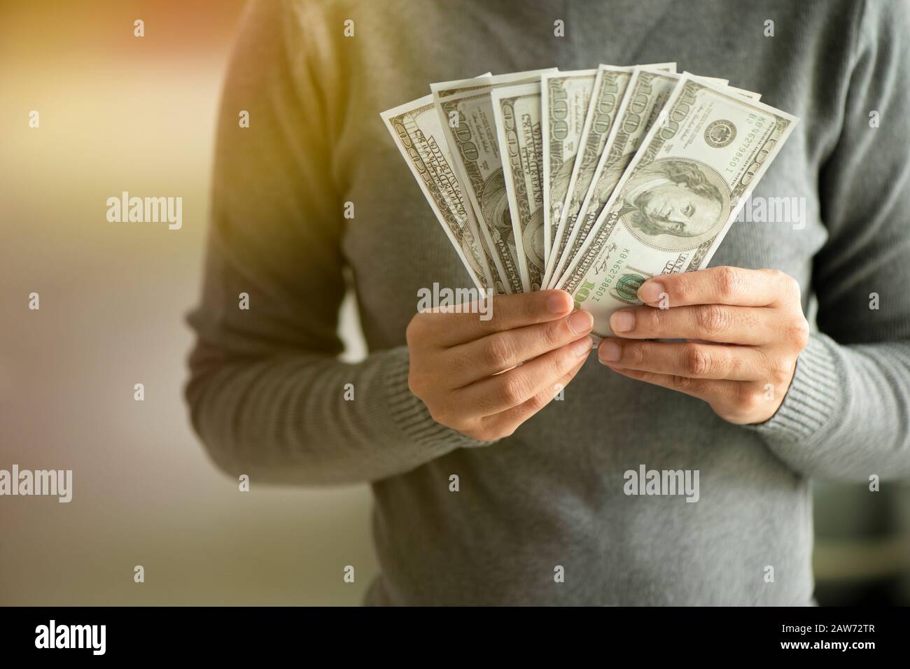 gros plan dollars entre les mains. Homme d'affaires en maillot gris tenant. Un ventilateur d'argent Banque D'Images