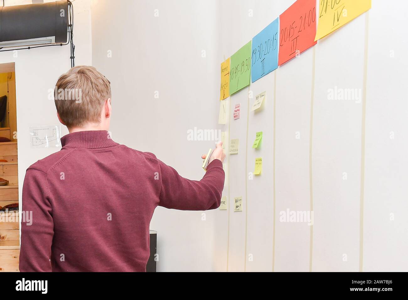 Homme aux cheveux bruns debout et pointant vers le tableau blanc enseignant la technique et la méthodologie de la mêlée agile pendant l'atelier à l'intérieur de l'espace de bureau Banque D'Images