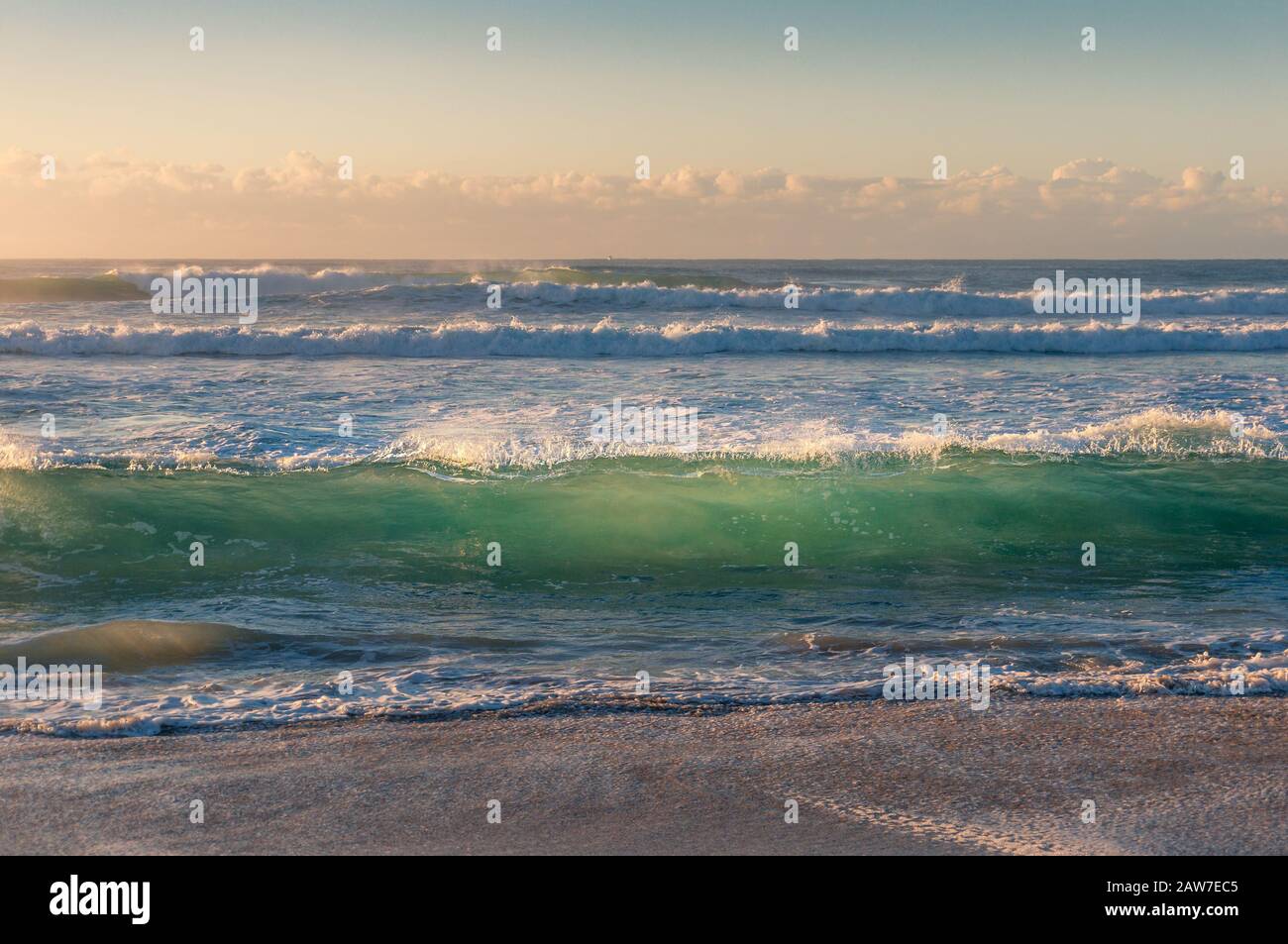 La vague bleue turquoise transparente s'enroule sur la plage de sable au lever du soleil. Mer nature fond Banque D'Images
