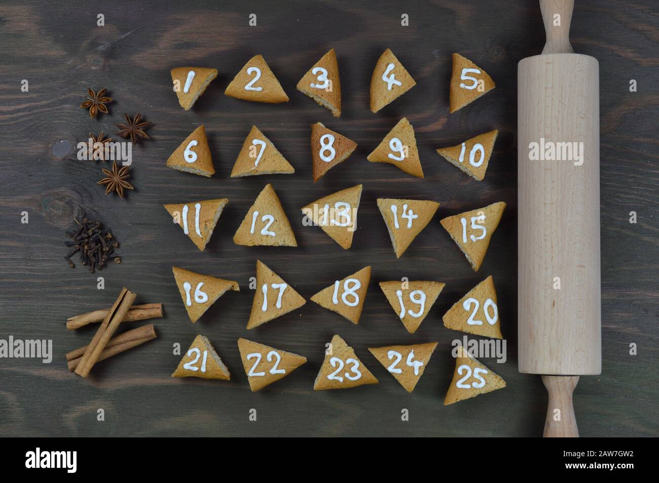 vingt-cinq biscuits de l'avent numérotés sur bois brun avec punaise et épices Banque D'Images