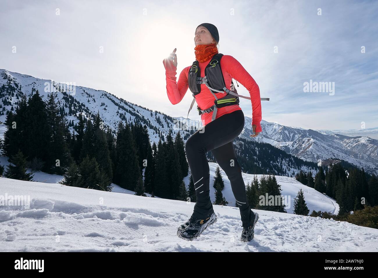Femme coureur de piste qui courir dans les montagnes d'hiver sur la neige. Course dynamique en montée sur piste femme athlète coureur vue latérale Banque D'Images