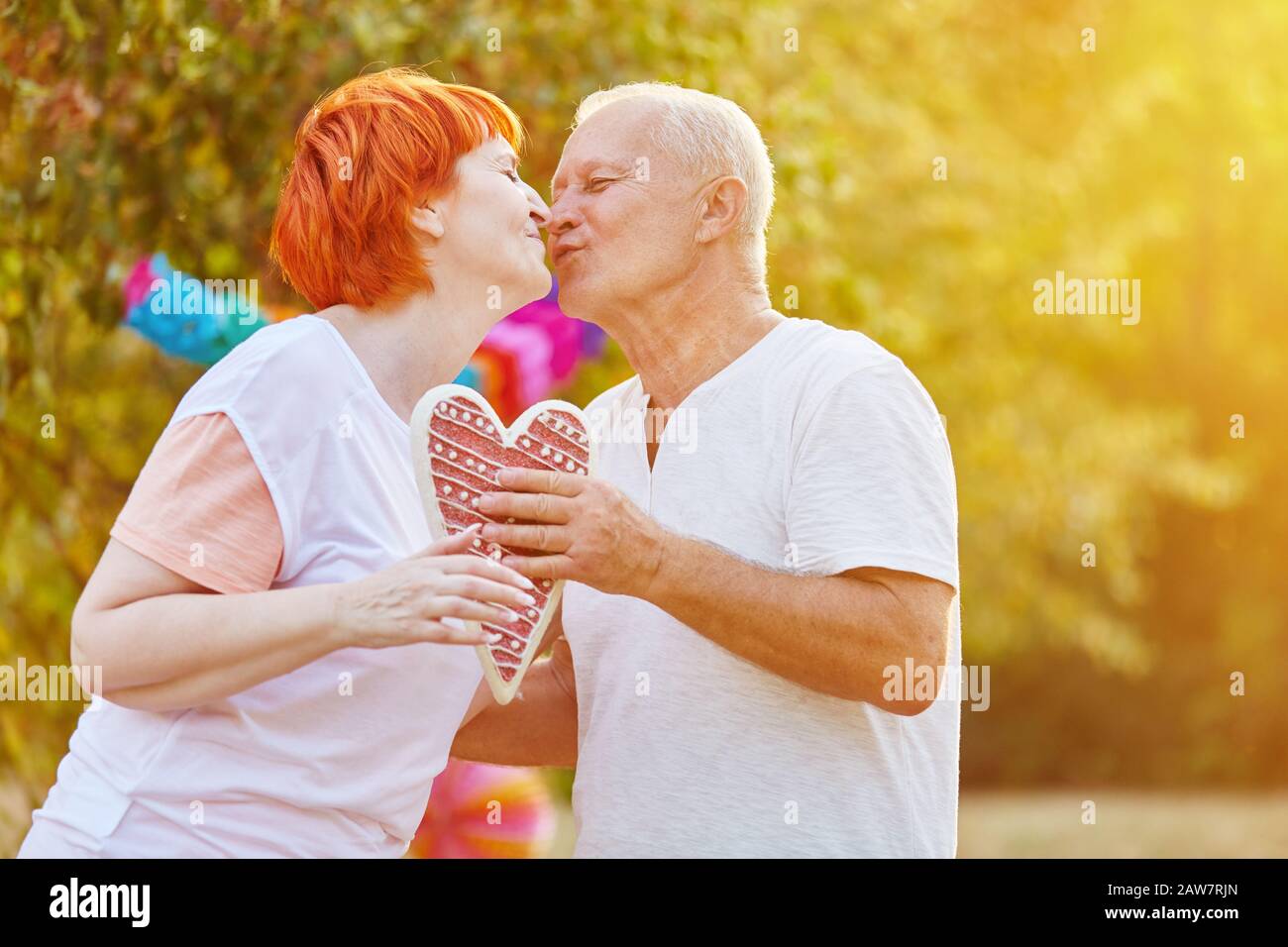 Couple dans l'amour les aînés ont un coeur tout en embrassant dans la nature Banque D'Images