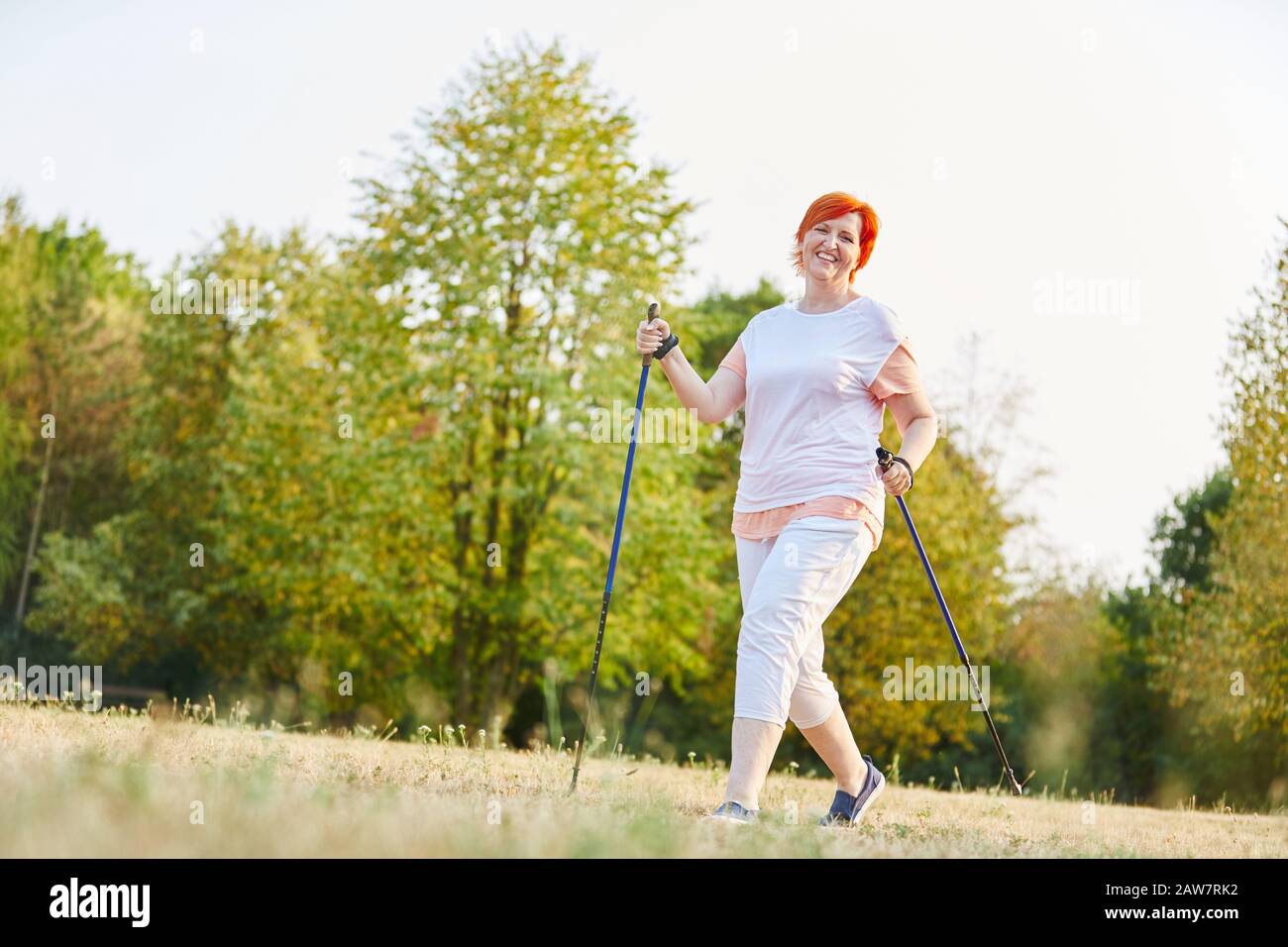 Heureuse femme faisant de la marche nordique en été dans le parc Banque D'Images