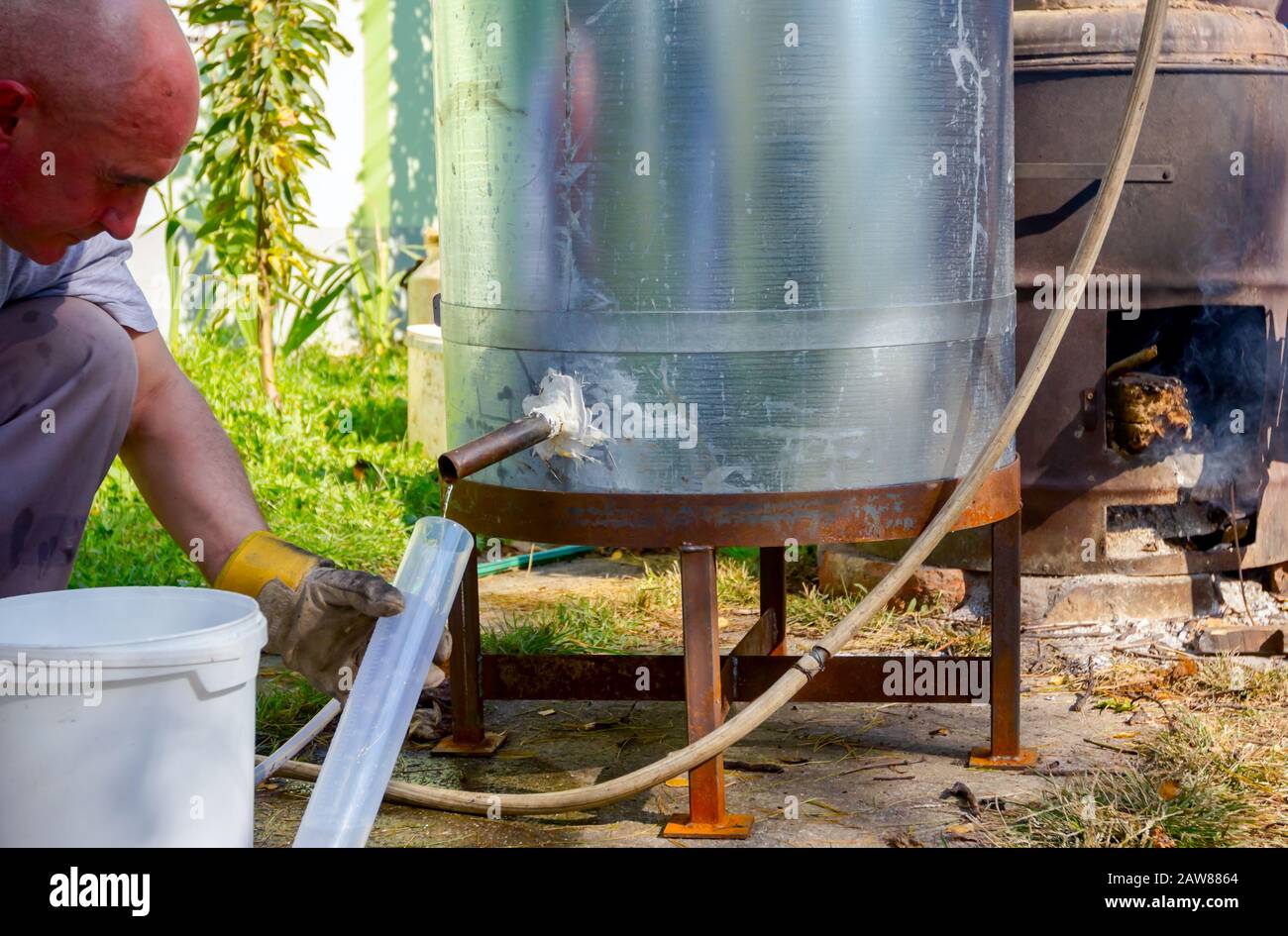 L'homme prend un échantillon de liqueur fraîchement distillée, alcool dans le cylindre gradué de laboratoire. Banque D'Images