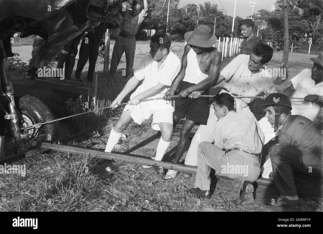 Atterrissage d'urgence d'un Curtiss P40 près de Solo Récemment, un avion de chasse Curtiss P40 s'est écrasé à la périphérie de Solo. Étant donné qu'il n'y avait pas de possibilité de fixer l'unité sur place et de la retirer sur le terrain de l'eau a été impossible, l'avion par l'armée a été traîné ailleurs pour être démonté. De nombreuses mains font du travail léger. Après beaucoup de yanking le téléphone enfin fossé Date: 13 avril 1949 lieu: Bondowoso, Indonésie, Java, Hollandais East Indies Banque D'Images