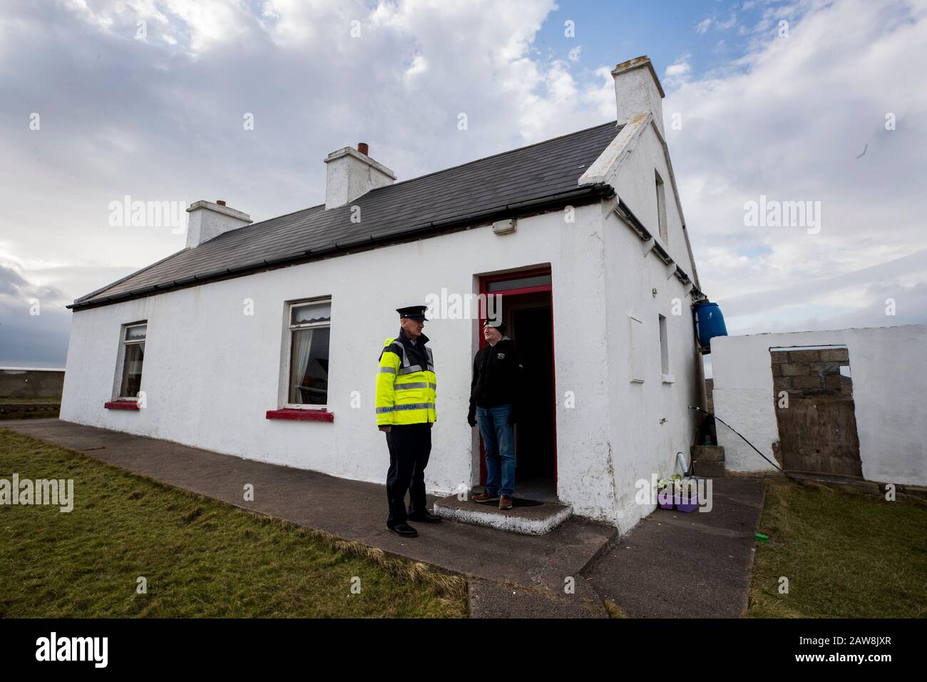 Charlie Sweeney (à droite) rencontre Garda Tom McBride après avoir voté lors de l'élection irlandaise de 2020 au bureau de vote de l'île Gola au large de la côte de Donegal, Irlande, Alors que les insulaires se rendent aux urnes un jour avant le reste du pays pour voter aux élections irlandaises. Banque D'Images