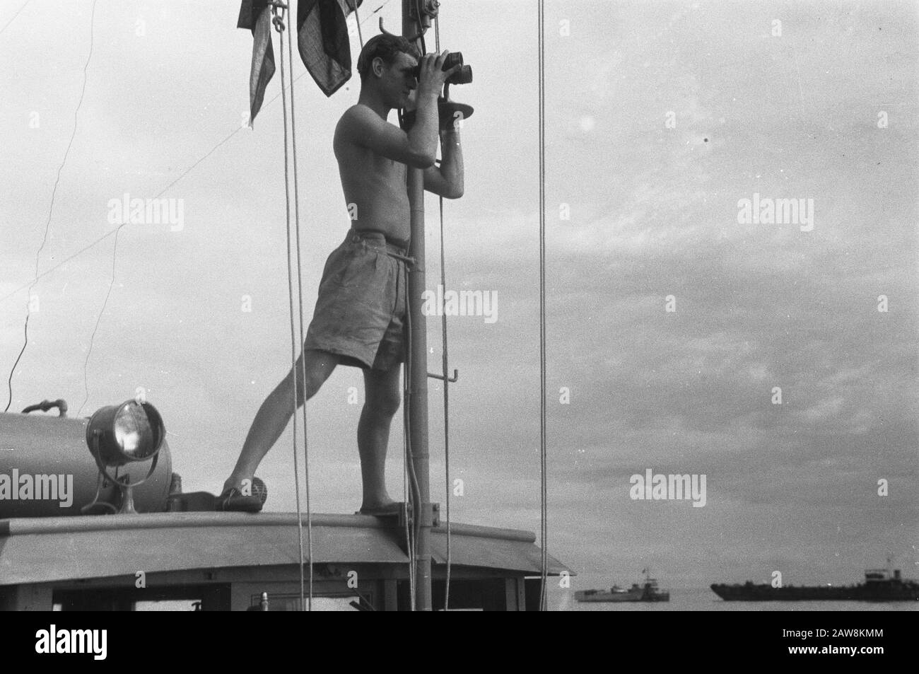 Photos libération Nord Sumatra [Soldier en short regardant à travers des jumelles debout sur un pont de vol d'un navire] Date : 19 décembre 1948 lieu : Indonésie , Antilles néerlandaises de l'est, Sumatra Banque D'Images