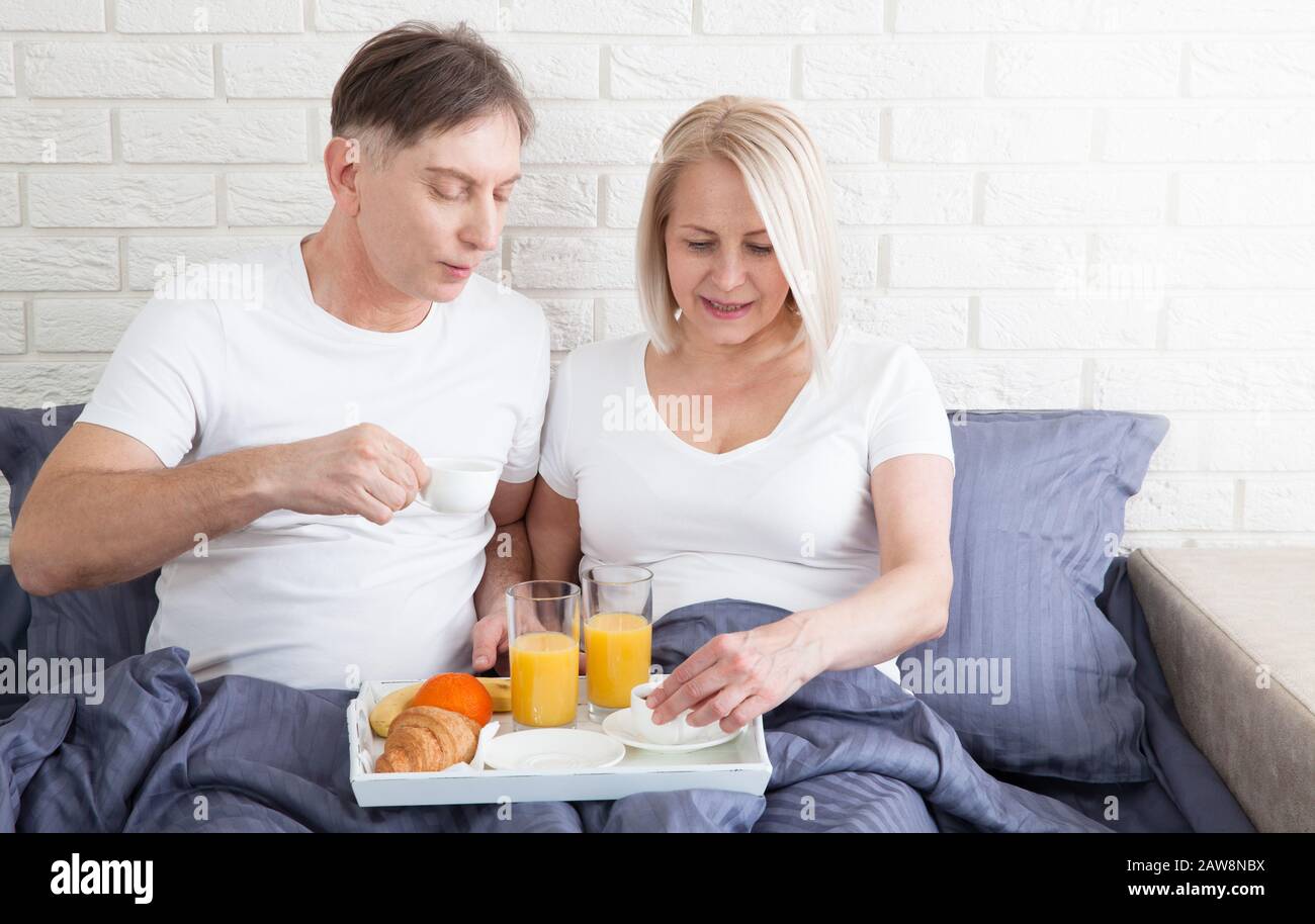 Couple romantique heureux ayant le petit déjeuner au lit à la maison Banque D'Images