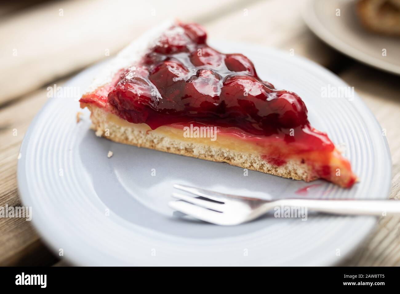 Tarte aux cerises sur une plaque, tranche sur une table en bois Banque D'Images