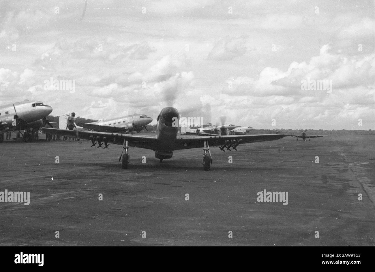 Atterrissage à Jambi; Avant le départ de Palembang Curtiss P51 Mustang combattant-bombardier avec six bombes sous les ailes d'un aéroport. Sur la gauche se trouve un homme de l'équipage du sol. Derrière deux autres Mustang à un homme sur l'aile. Sur le côté de la voie fiscale sont Dakotas up Date: 30 décembre 1948 lieu: Indonésie, Hollandais East Indies, Sumatra Banque D'Images