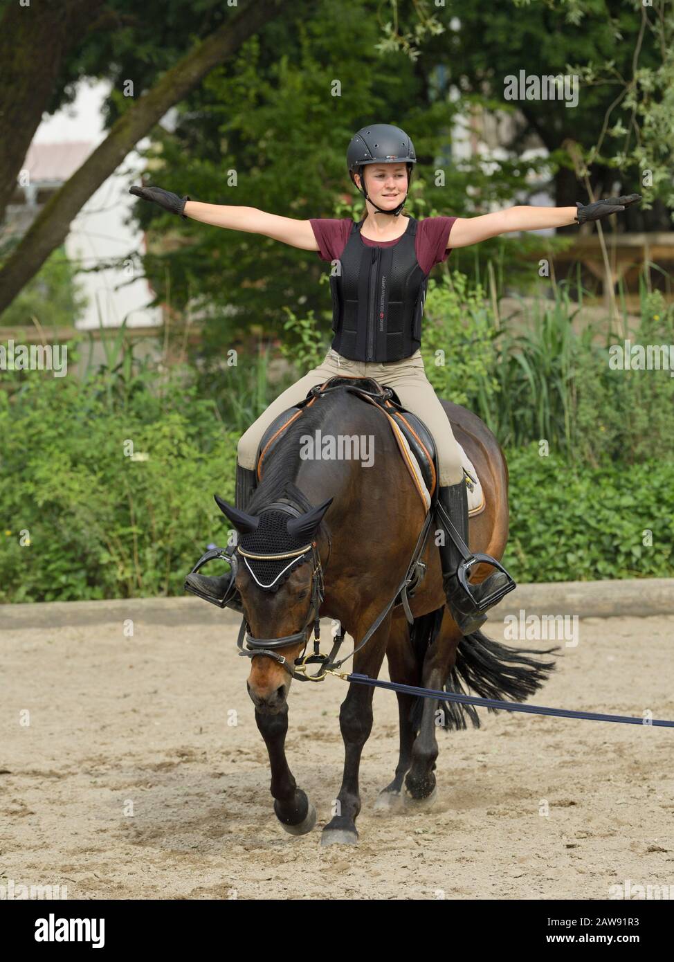 Leçon d'équitation en fente, une fille portant un casque et un protecteur de dos de cheval sur poney allemand Banque D'Images