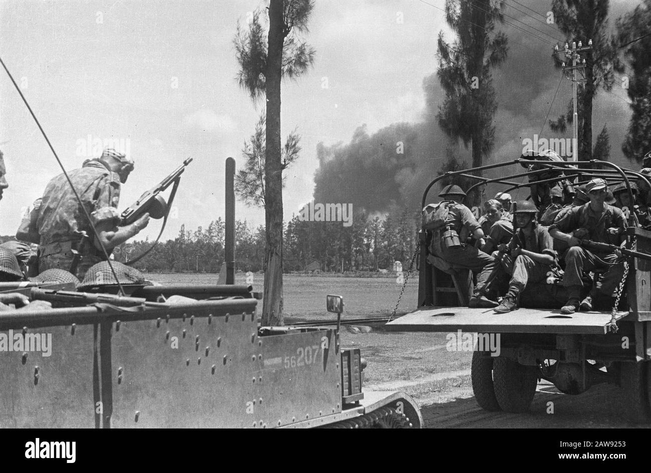 La montée de la V-brigade a laissé un soldat avec un tommy-gun sur un transporteur de production. Pour lui, un camion rempli de soldats armés. Au loin un panache noir Date: 12/01/1948 lieu: Indonésie Hollandais East Indies Banque D'Images