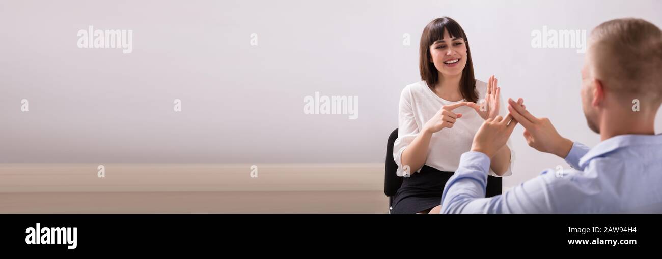 Souriante jeune femme et l'homme parle avec la langue des signes sur fond blanc Banque D'Images