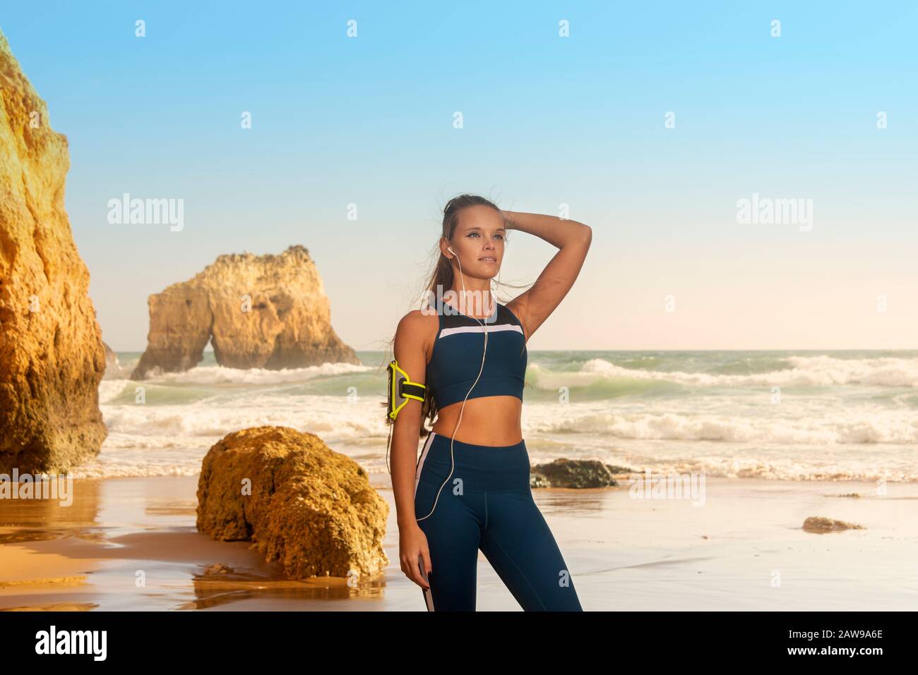 une femme sportive portant des vêtements de sport et un brassard pour smartphone, debout au bord de la mer Banque D'Images