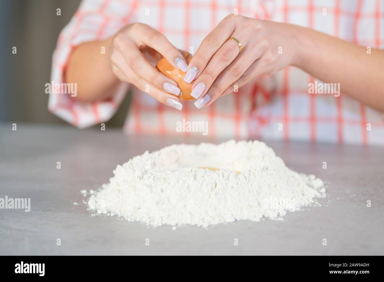 Femme ajoutant un œuf à un moulus de farine Banque D'Images
