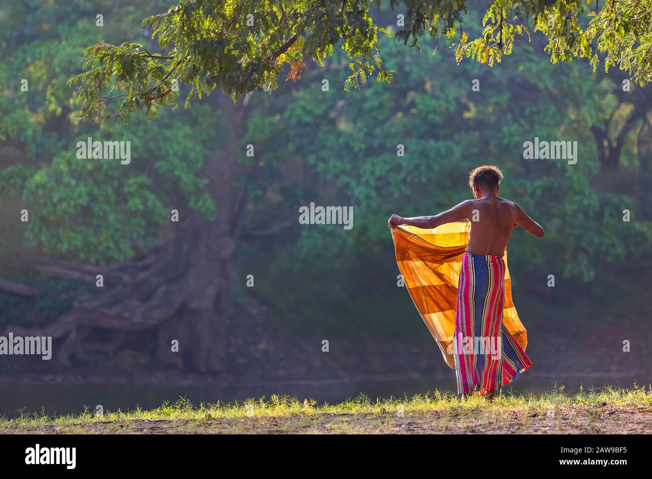 Homme local repliant son sarong après s'être baigné au coucher du soleil, Kataragama, Sri Lanka Banque D'Images