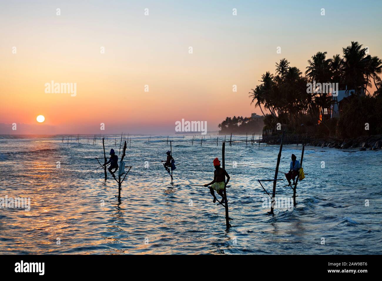 Pêcheurs sur pilotis en silhouette au coucher du soleil, Sri Lanka Banque D'Images