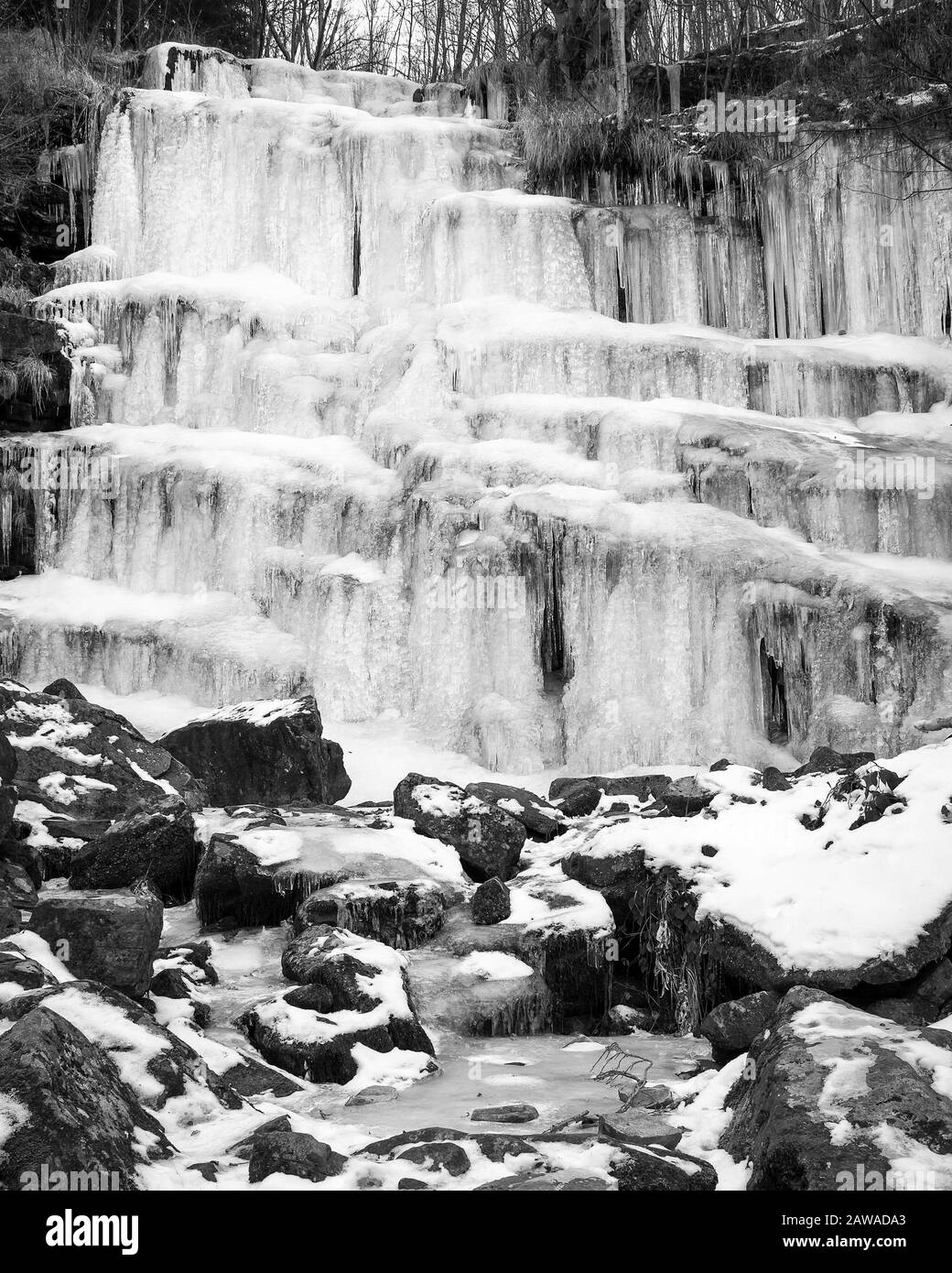 Noir et blanc, belle, pittoresque, gelée Tupavica chute d'eau avec des icules suspendues et de montagne creek avec des roches orange et des feuilles tombées Banque D'Images