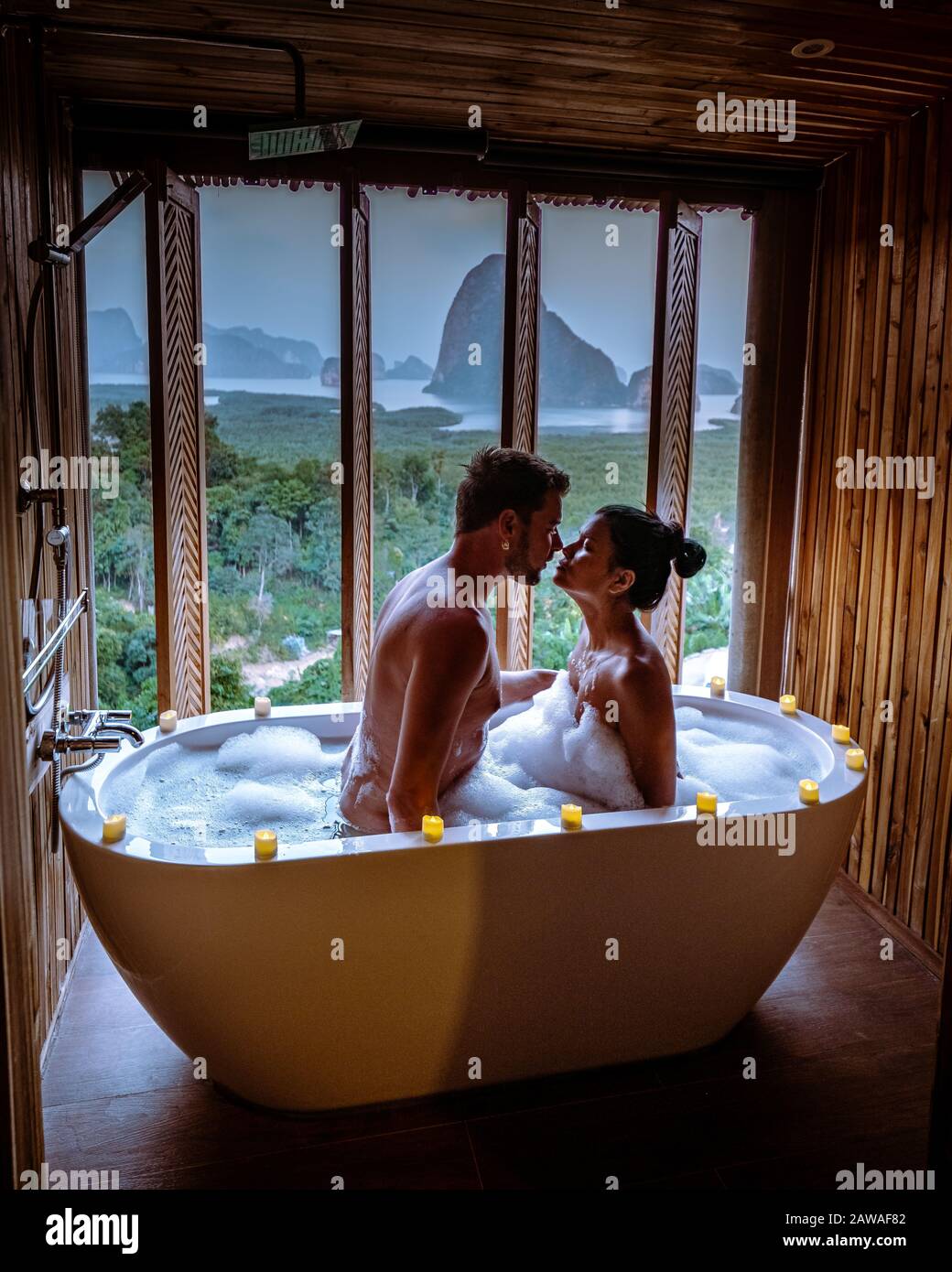 Couple regardant le coucher du soleil dans la baignoire dans la salle de  bains pendant les vacances en Thaïlande regarder le coucher du soleil sur  l'océan et les métnains Photo Stock -