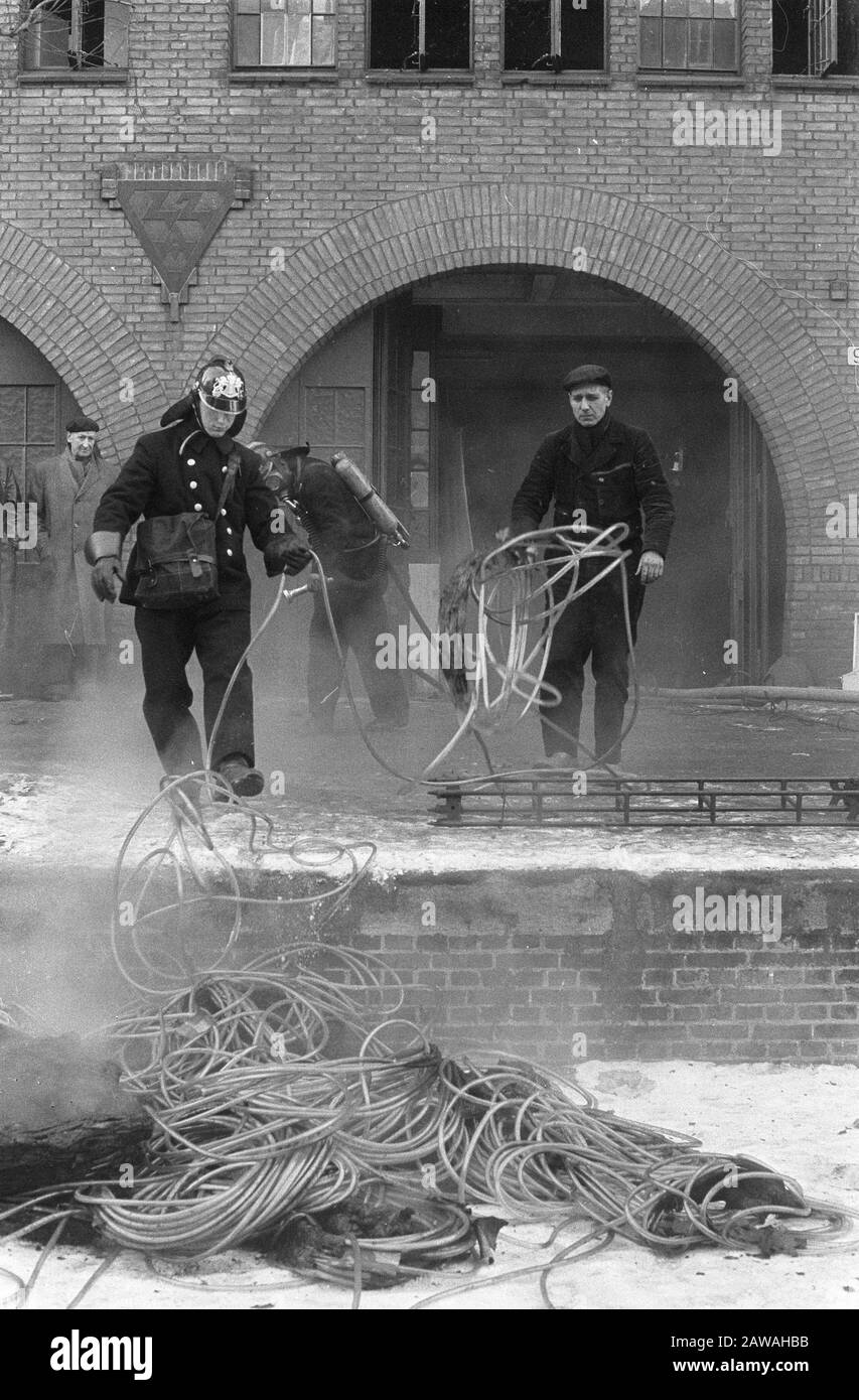 Feu moyen dans le matériel Vente en gros Van Leeuwen à Groenburgwal 3-17, les tuyaux en plastique sont jetés sur la glace à partir de la Groenburgwal / Date: 26 février 1963 mots clés: TUYAU de jardin, personne brûlante Nom: Lions Banque D'Images