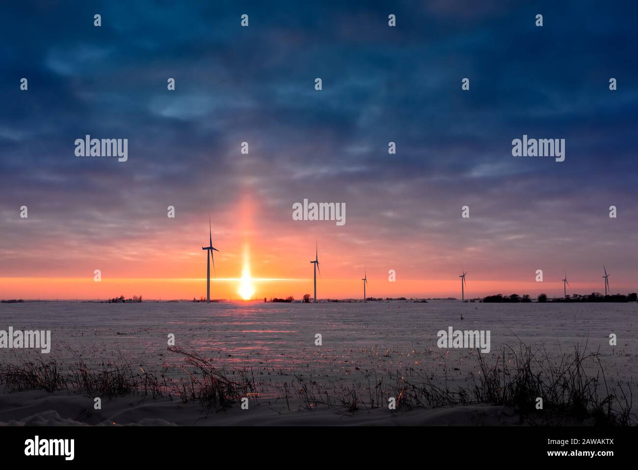 Un chien de soleil se plaçant au-dessus de l'horizon au-dessus d'une ferme en hiver dans l'Iowa Banque D'Images