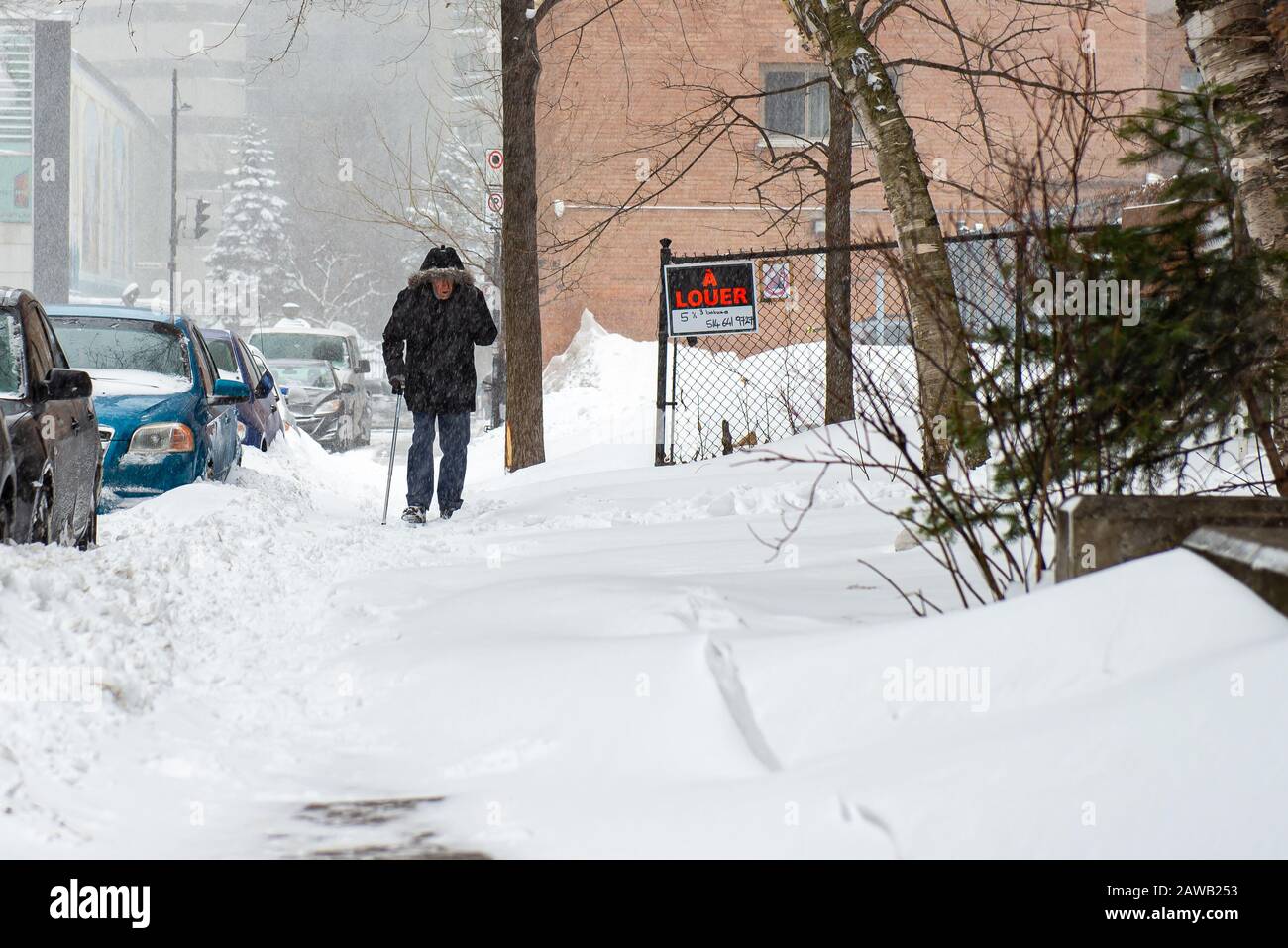 Montréal Québec Canada le 6 février 2020 : homme âgé de canne marchant sur une route enneigée pendant une tempête de neige Banque D'Images