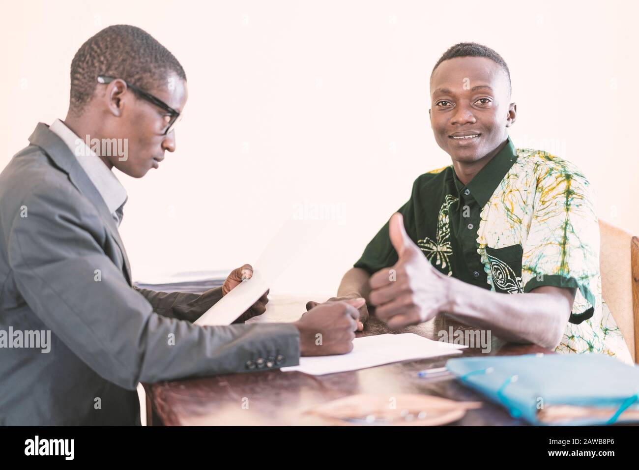 Beau et jeune étudiant africain souriant et montrant des pouces vers le haut symbole gai portrait avec le patron officiel de la compagnie Banque D'Images