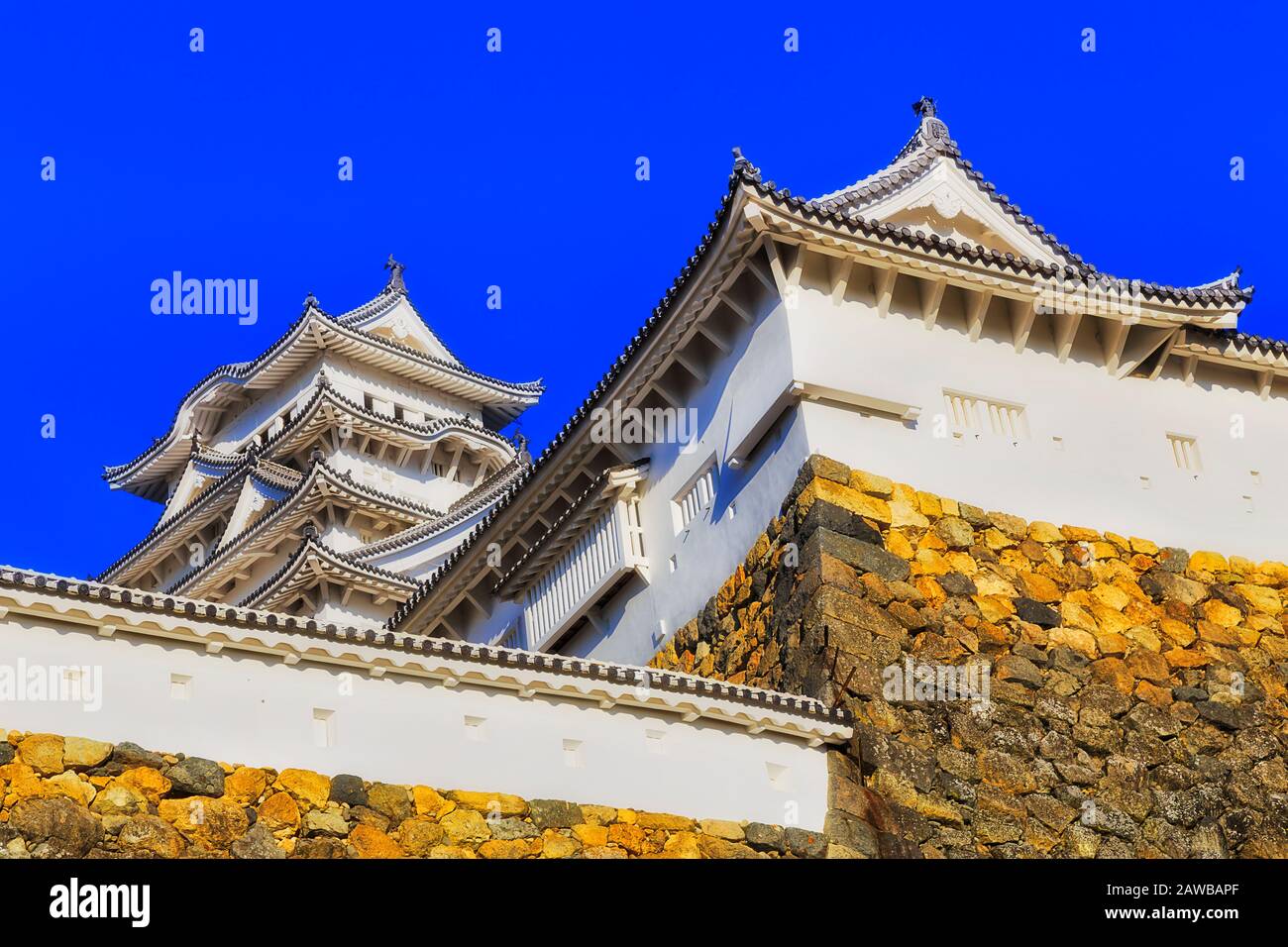 Hauts des tours historiques dans le château japonais de shogun près de la ville d'Osaka au-dessus des murs en pierre sous le ciel bleu. Banque D'Images