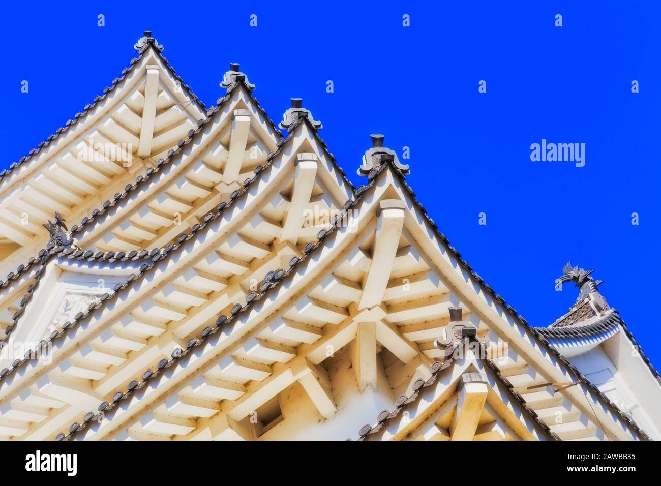 Architecture japonaise traditionnelle - coins de toit superposé avec poutres et structure intérieure contre le ciel bleu dans l'un des châteaux historiques. Banque D'Images