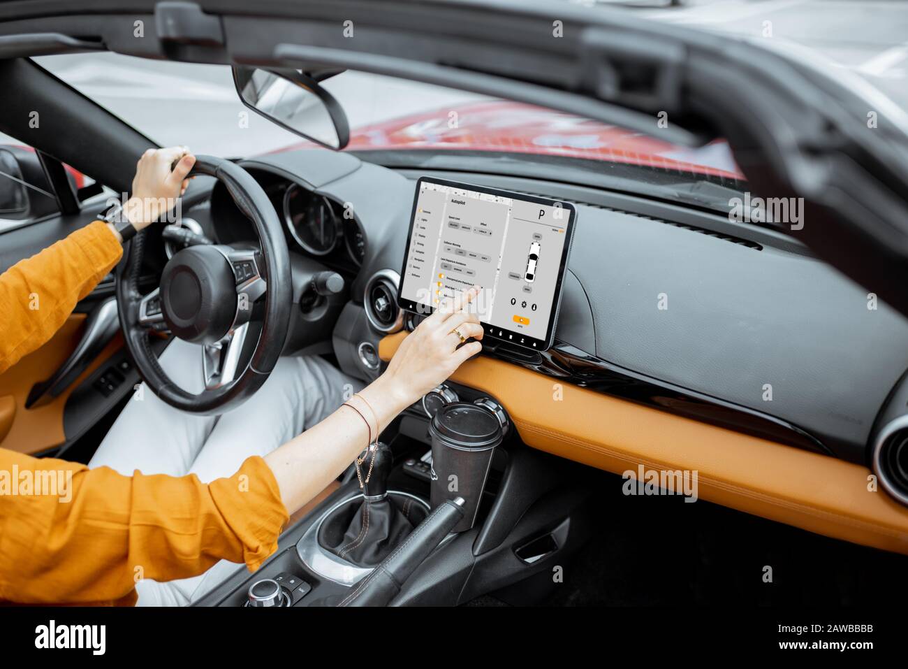 Une femme gaie qui contrôle la voiture avec un tableau de bord numérique, qui change de mode pilote automatique en conduisant un cabriolet. Concept de voiture intelligente Banque D'Images