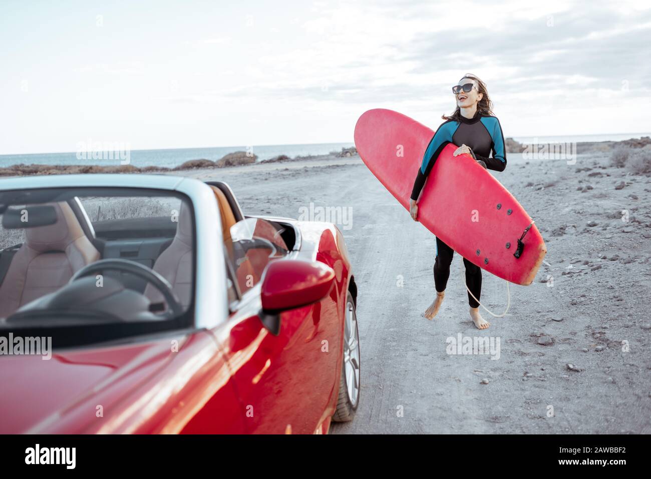 Portrait d'une jeune femme surfant en maillot de bain marchant avec planche  de surf sur la route de terre près de l'océan. Style de vie actif et  concept de surf Photo Stock -