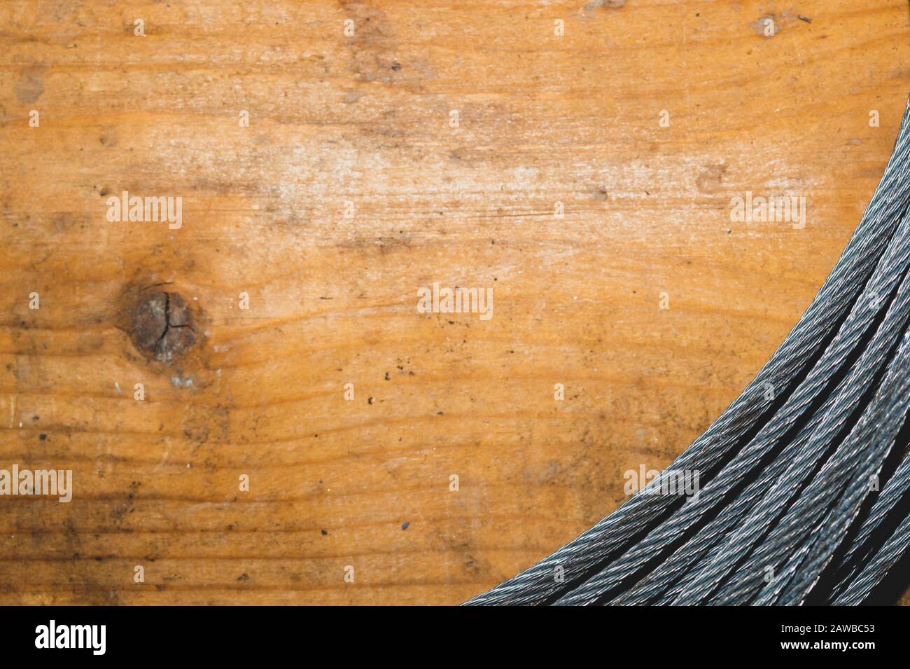 Câble en acier sur fond en bois. La tige de corde métallique repose sur la table. Outil de travail Banque D'Images