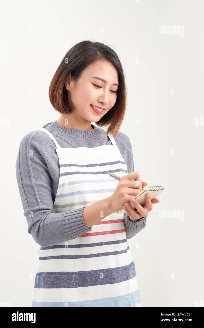 Portrait de la tête de la serveuse souriante portant un tablier noir prêt à prendre commande client, femme attrayante avec ordinateur portable et stylo dans les mains regardant CA Banque D'Images