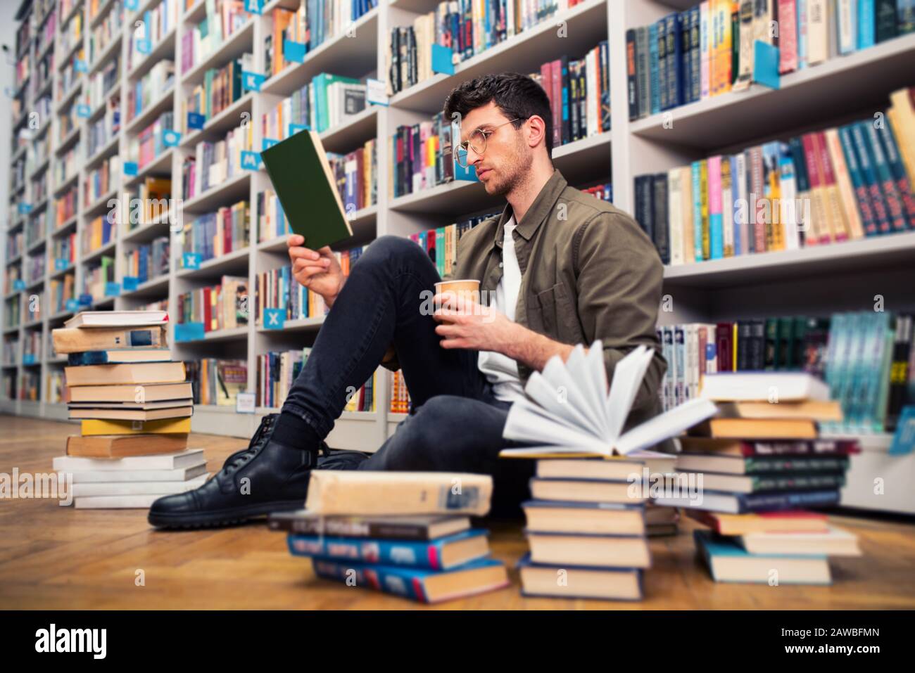 Garçon lit un livre dans une bibliothèque. Concept de curiosité, d'imagination et de culture Banque D'Images
