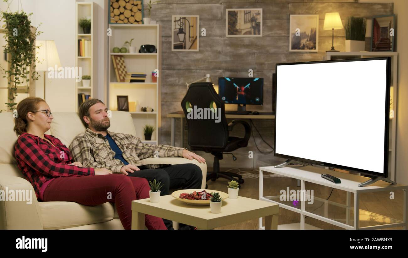 Couple se reposant sur un canapé regardant sur la télévision avec écran vert. Zoom avant. Banque D'Images