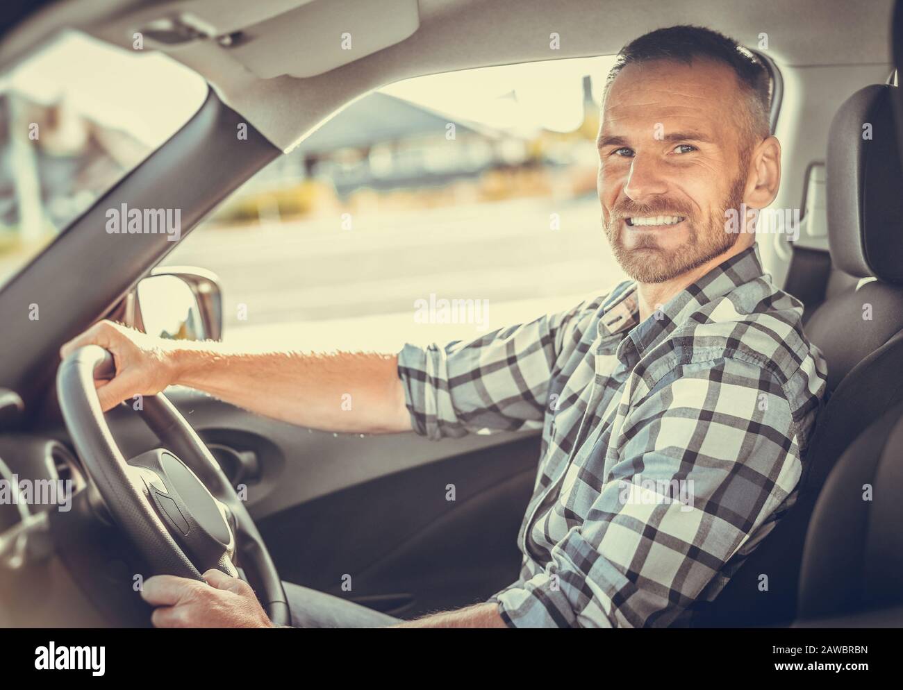 Homme séduisant au volant d'une voiture blanche. Banque D'Images